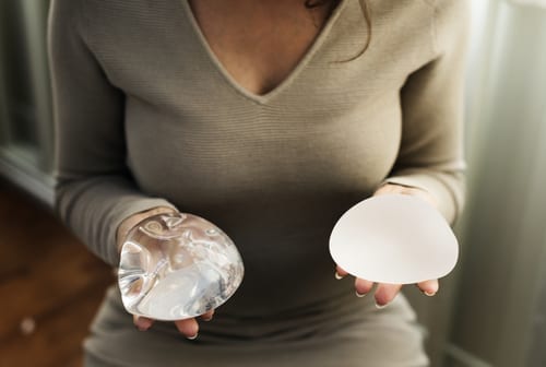 Woman Holding Saline and Silicone Breast Implants