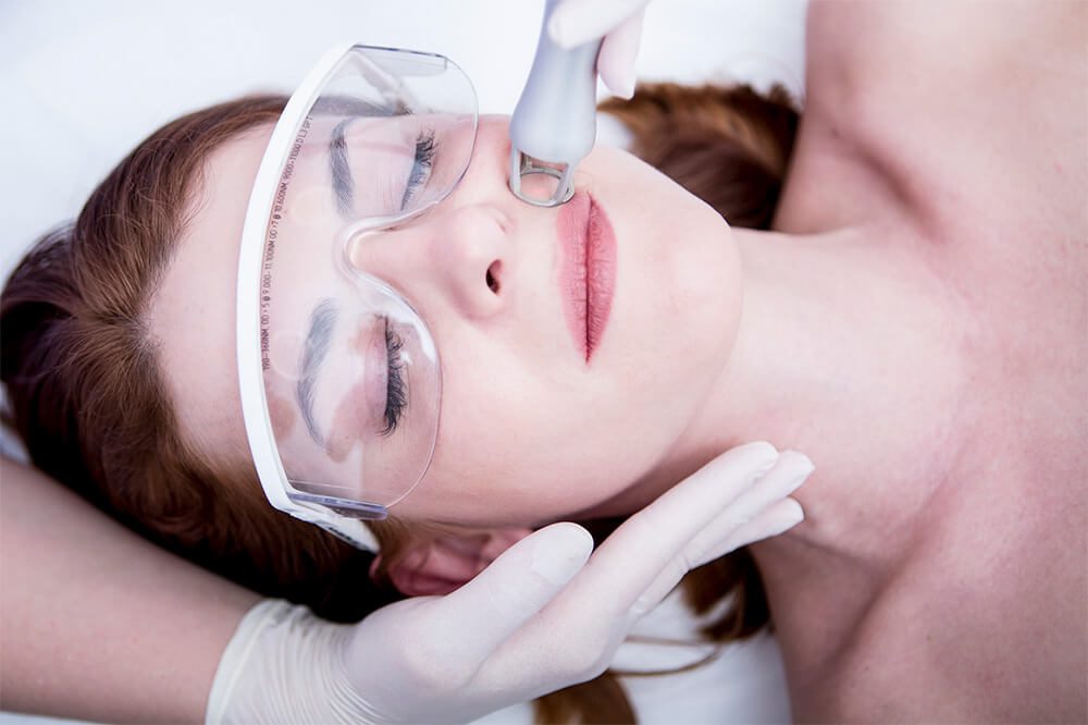 Female patient with protective glasses getting facial treatment